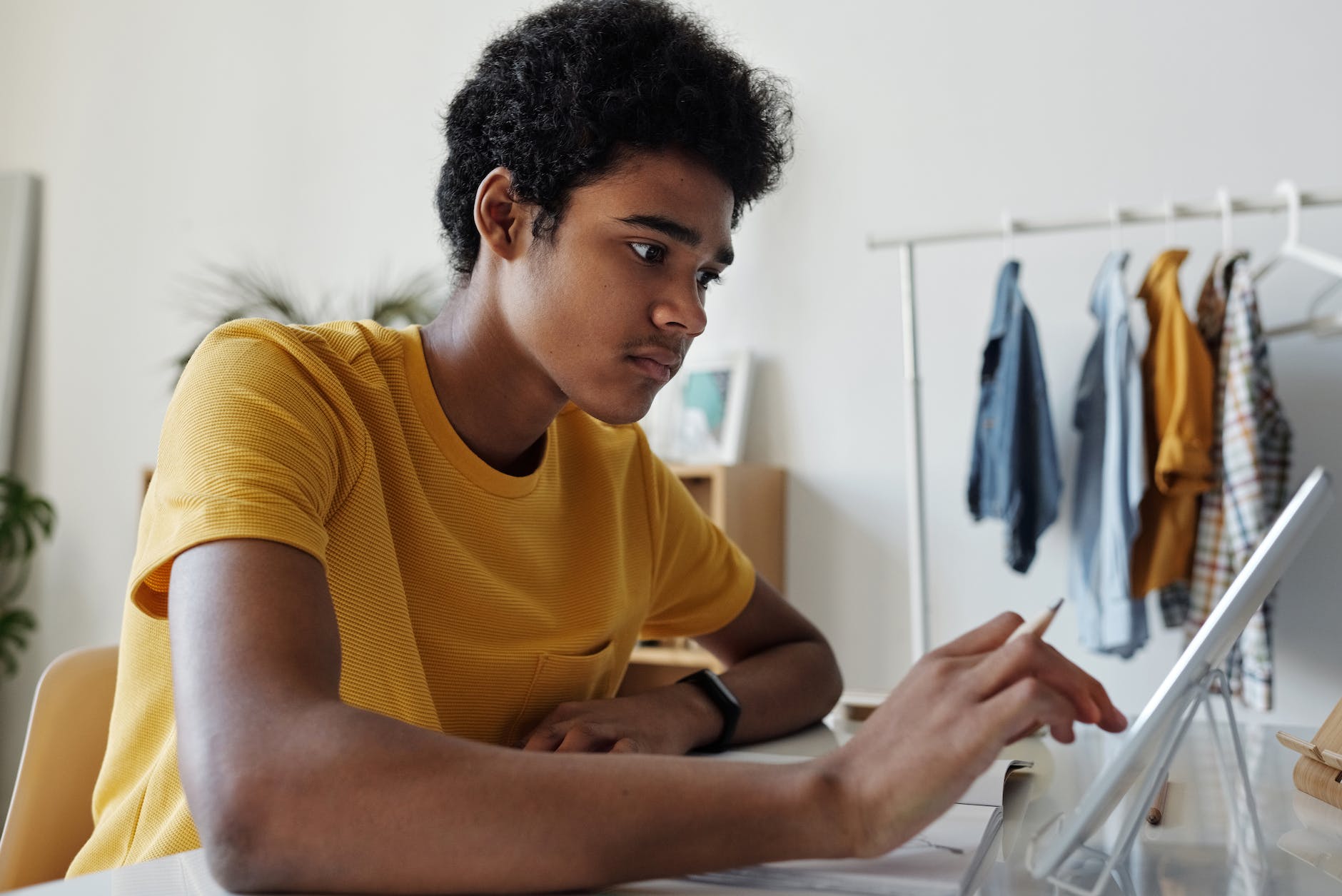 man in yellow crew neck t shirt while using tablet apps to help with revision