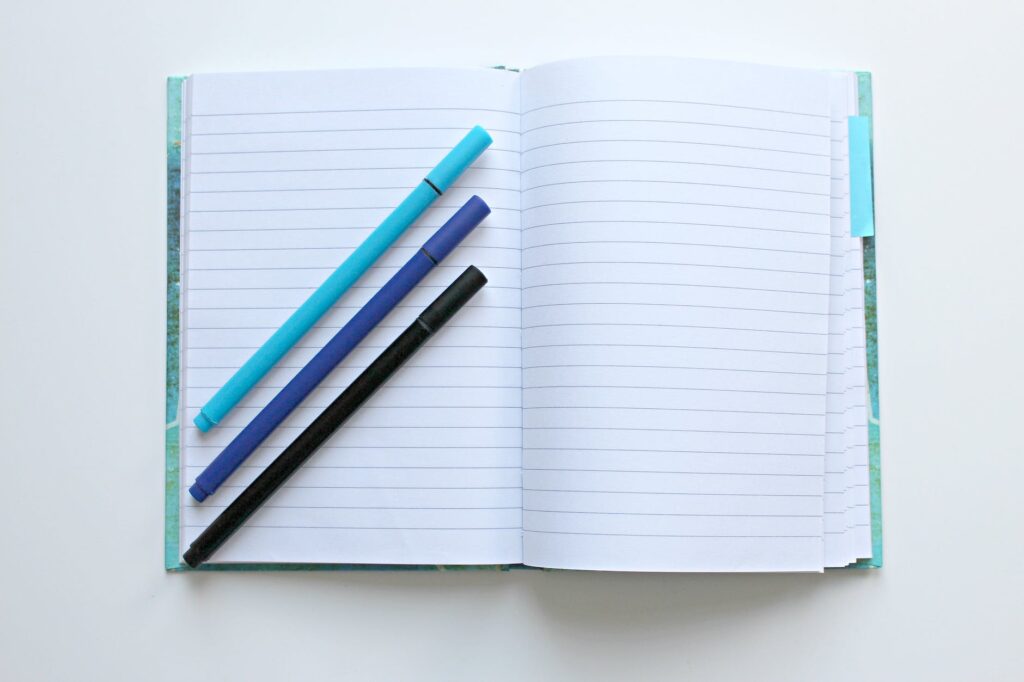 opened notebook with three assorted color pens